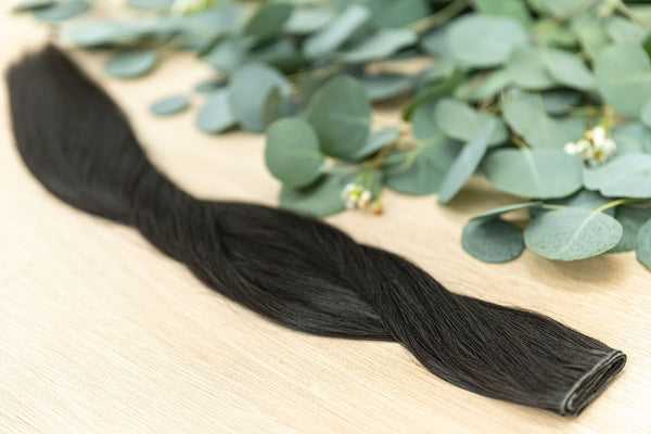 EBONY HIBER WEFT Ebony Hiber Weft is a 22" weft is a natural level 1 dark brown with a warm undetone. These wefts offer customization options, including custom sizing, cut, and a seamless fine root base without a return edge. The Hiber Wefts are 22" in le